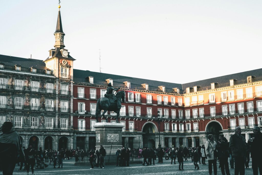 A lively scene at Plaza Mayor, Madrid, featuring historic architecture and a statue.